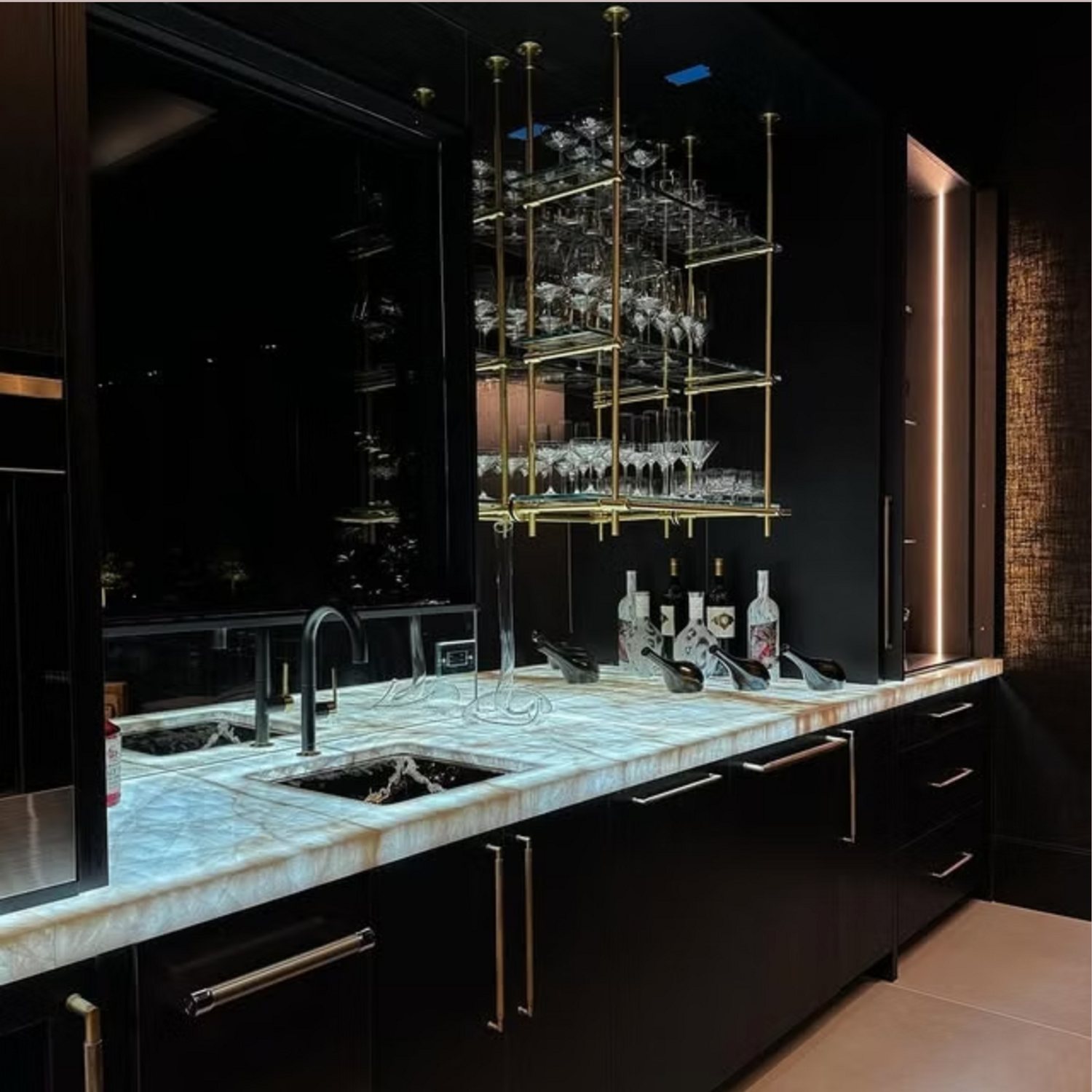 Custom black bar with onyx countertop and brass glassware rack by Hannah Brooke Design